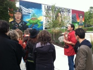 Alan Gross discusses the mural in the background, which illustrates the Ojibwe origin story.